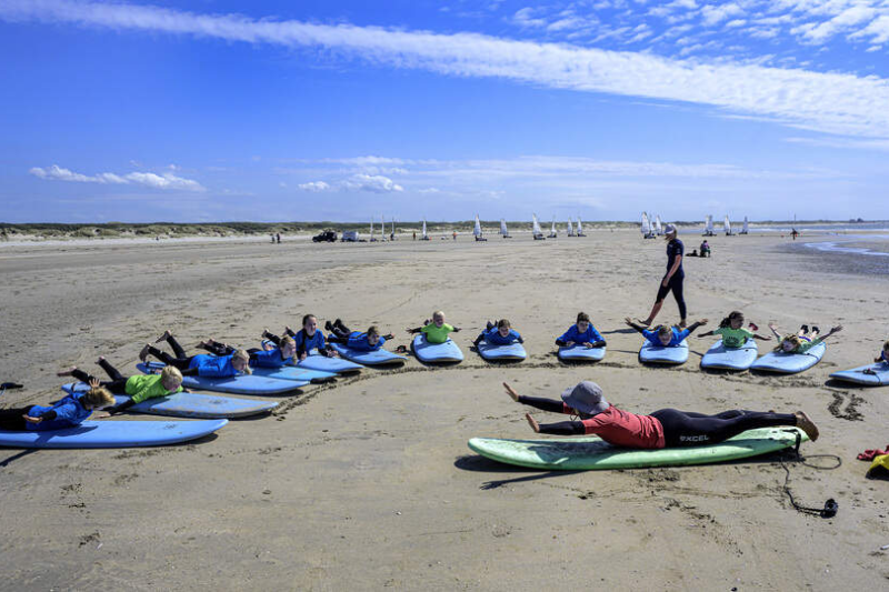 Kinderen surfen bij strandpaviljoen Hightide op het IJmuiderstrand